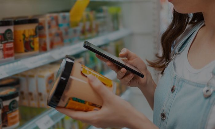 imagem representativa de mulher com celular na mão vendo validade de produto no supermercado simbolizando o titulo do artigo Sistema para Validade de Produto